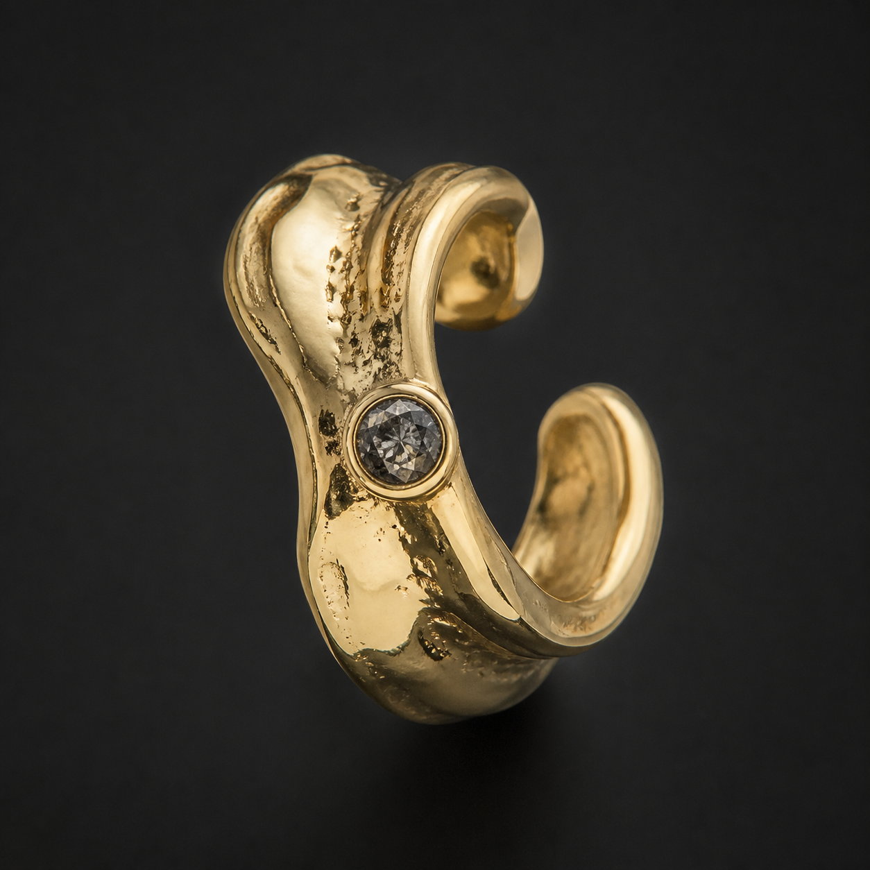 Photograph of a sculptural gold ear cuff with a smoky stone