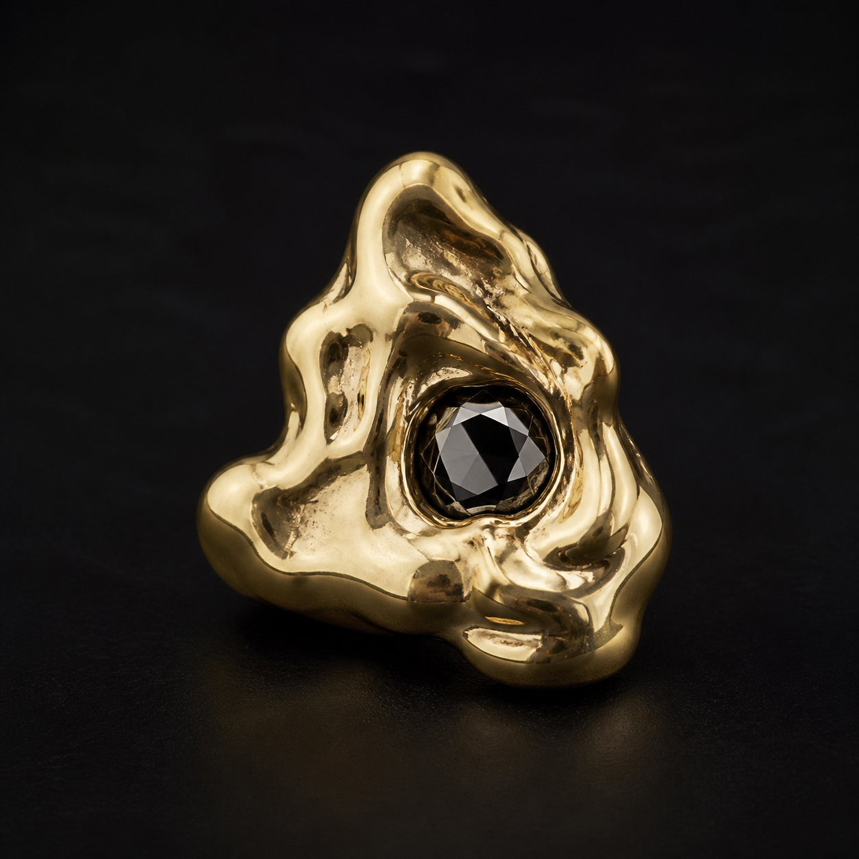 Photograph of a molten gold sculptural object with a black diamond